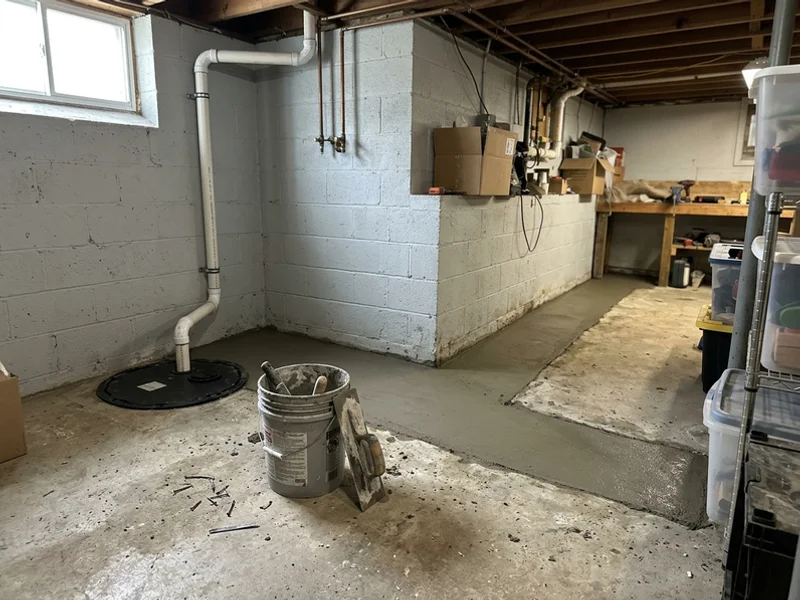 Interior French drain channel and sump basin in a finished basement perimeter