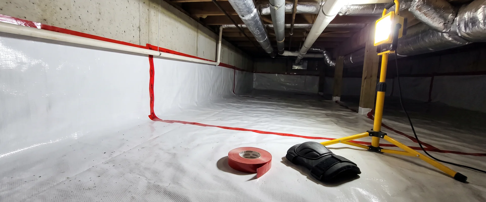 Encapsulated crawl space with a bright white taped vapor barrier running up the foundation walls